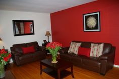 a living room with two couches and a coffee table in front of the red wall