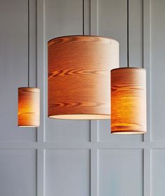 three wooden lamps hanging from the ceiling in a room with white walls and wood paneling