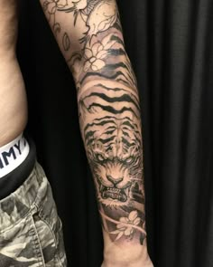 a man with a tiger tattoo on his arm next to another person's arm