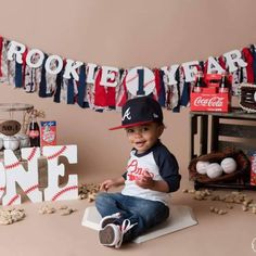 a young boy sitting on top of a table next to baseballs and other items