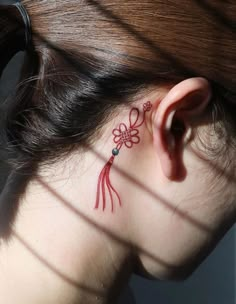 a woman with a tattoo on her neck and behind her ear is looking to the side