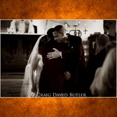 a man and woman embracing each other in front of a church alter with the priest standing behind them