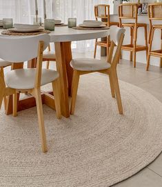 a dining room table with chairs and a rug on the floor in front of it