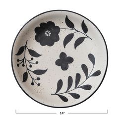 a black and white plate with flowers painted on the side, sitting in front of a white background