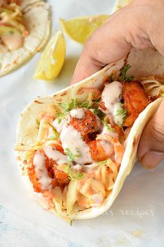 a hand holding a taco filled with shrimp and sauce