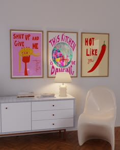 three posters hang on the wall above a white dresser with a lamp in front of it