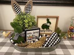 a basket filled with fake grass and some bunny ears on top of a checkered table cloth