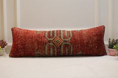 a red pillow sitting on top of a white floor next to potted plants and flowers