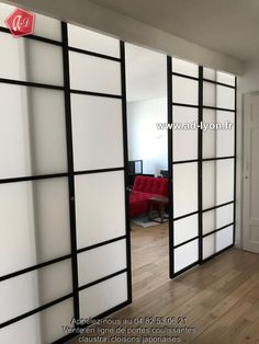 an empty room with white and black sliding doors on the wall, in front of a red chair