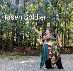 a woman standing in front of trees with the words risen soldier above her