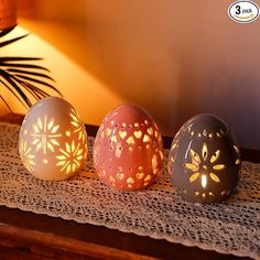 three decorative eggs sitting on top of a table