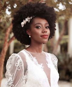 a woman with an afro wearing a white dress and flower in her hair is posing for the camera