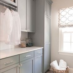 a laundry room with gray cabinets and white linens