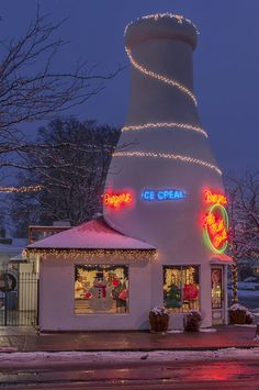 an ice cream shop is lit up at night with christmas lights on the roof and windows