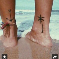 two people with matching tattoos on their feet standing in the sand at the beach,