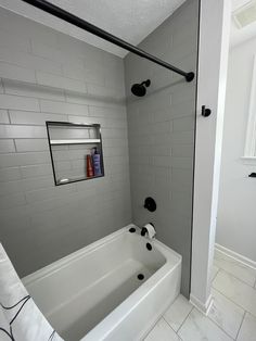 a bathroom with a white tub and black shower faucet next to the toilet