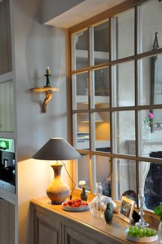 a lamp is sitting on a table next to a window with panes in it