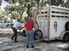 two men loading a horse trailer onto the back of it