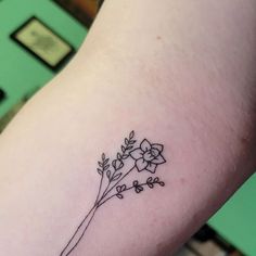 a small flower tattoo on the left side of the right arm is shown in black ink