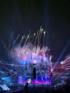 fireworks are lit up in the night sky above an arena with people watching from seats