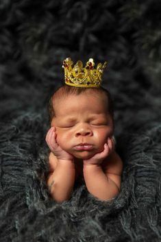 a newborn baby wearing a gold crown on top of it's head