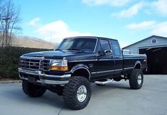 a black pickup truck parked in front of a garage with two large tires on it