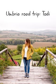 a woman standing on a wooden bridge with the words umbria road trip toi