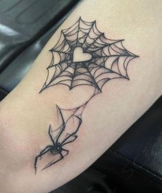 a spider web tattoo on the arm with a heart in it's center piece