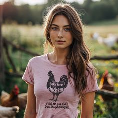 Express your unique sense of humor and independent spirit with our "Buy Me Chickens and Tell Me You Don't Trust the Government" graphic tee. This one-of-a-kind shirt will surely spark conversations and smiles wherever you go. This shirt isn't just a piece of clothing; it's a statement. Whether you're a backyard chicken enthusiast, a lover of witty apparel, or someone who enjoys a good laugh, this tee is for you. Wear it to showcase your unique personality and your stance on the unconventional. P Novelty Cotton Tops With Text Print, Cotton Novelty Top With Text Print, Novelty Cotton Tops With Letter Print, Novelty Short Sleeve Tops With Text Print, Fitted Novelty Tops With Graphic Print, Novelty Cotton Tops With Screen Print, Pink Novelty Tops With Funny Print, Novelty Relaxed Fit Short Sleeve Tops, Funny Pink Tops With Screen Print