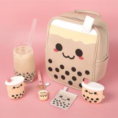 a lunchbox with two cups and a drink in it on a pink surface next to other items