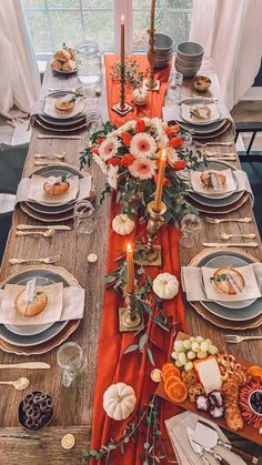 the table is set with plates, silverware and orange napkins for an elegant thanksgiving dinner