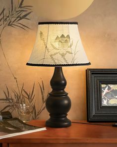 a lamp that is on top of a table next to a framed photo and an empty glass