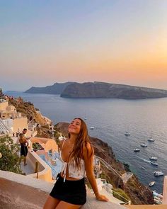 a woman standing on top of a cliff next to the ocean