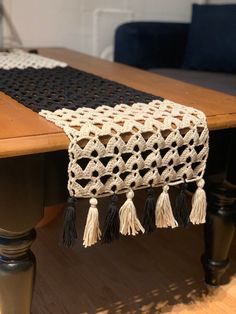 a table runner with tassels on it sitting on top of a wooden table