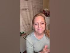 a woman sitting in front of a bathroom sink with her hand up to the camera