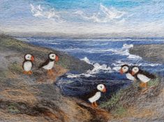 three puffins are standing on the rocks by the water