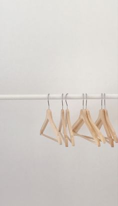 four clothes hangers are hanging on a white wall