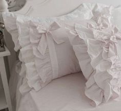 two white pillows with ruffled edges on a bed