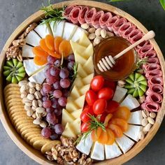 a wooden platter filled with different types of cheeses and meats, nuts and fruit