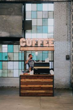 a man standing in front of a coffee shop talking on a cell phone while holding a camera