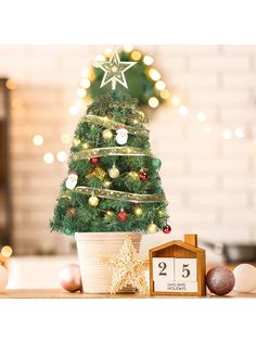 a small christmas tree sitting on top of a table next to a clock and other decorations