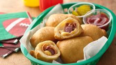 a green basket filled with pastries next to fruit and ketchup on top of a wooden table