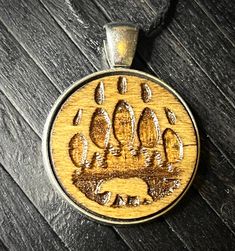 a wooden pendant with an animal's paw print on it, sitting on a table