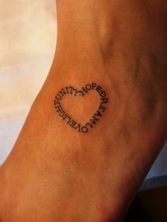 a small heart tattoo with the word love written in it on someone's foot