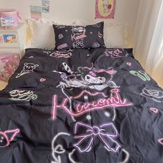 a black bed with pink and white drawings on the comforter, pillows and pillow cases