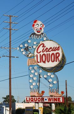 a sign for a liquor store with a clown holding a wine glass in it's hand