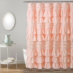 a shower curtain with ruffles and a mirror in the corner next to it