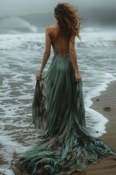 a woman in a dress standing on the beach