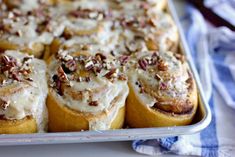 a pan filled with rolls covered in cheese and pecans