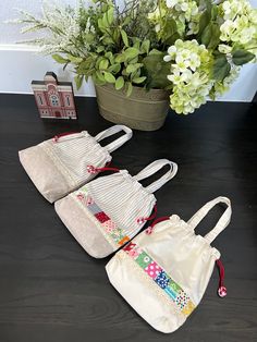 three white purses sitting on top of a table next to a potted plant